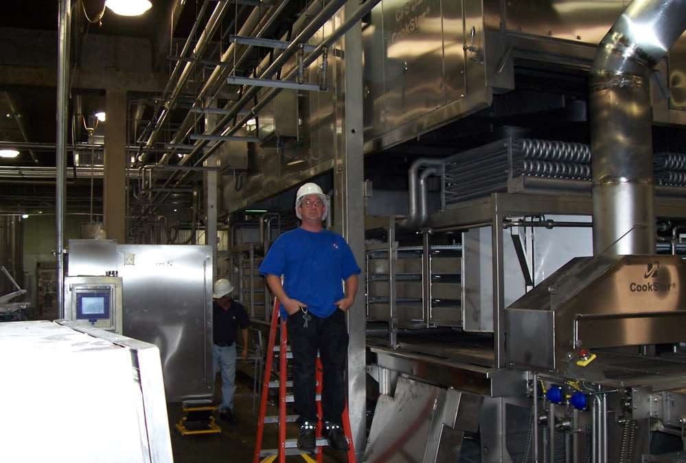 Jonathan Haymans in front of equipment working as a field service equipment engineer
