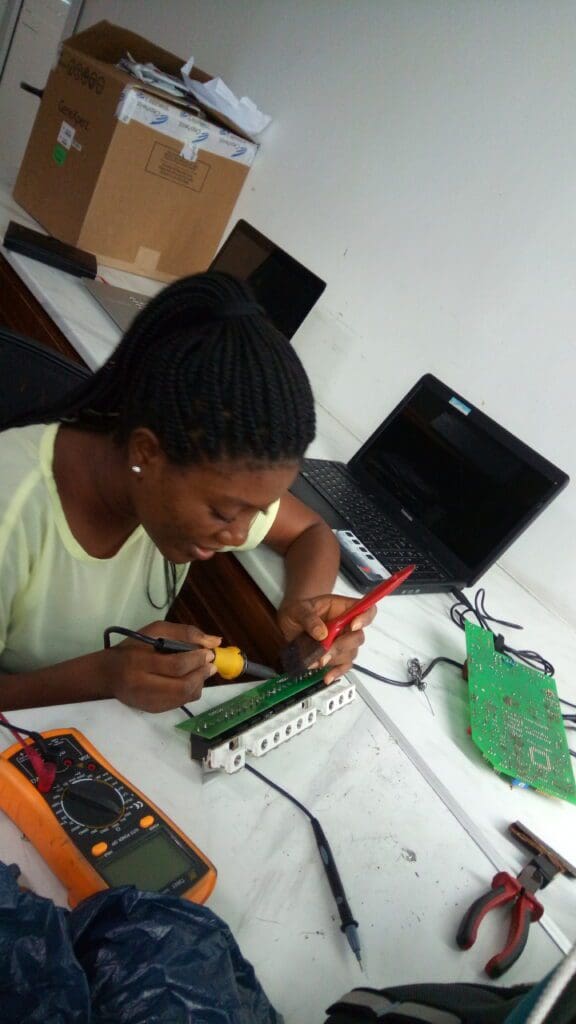 Elise Kafui Ayi woman biomedical engineer at tool bench fixing circuit board