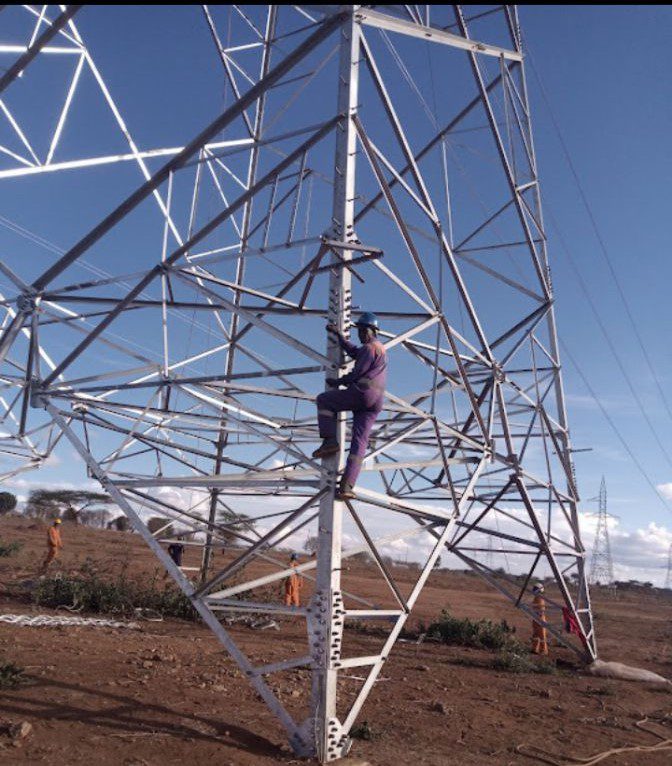 Kelvin Mwikya working on power lines connecting power plants climbing pylon
