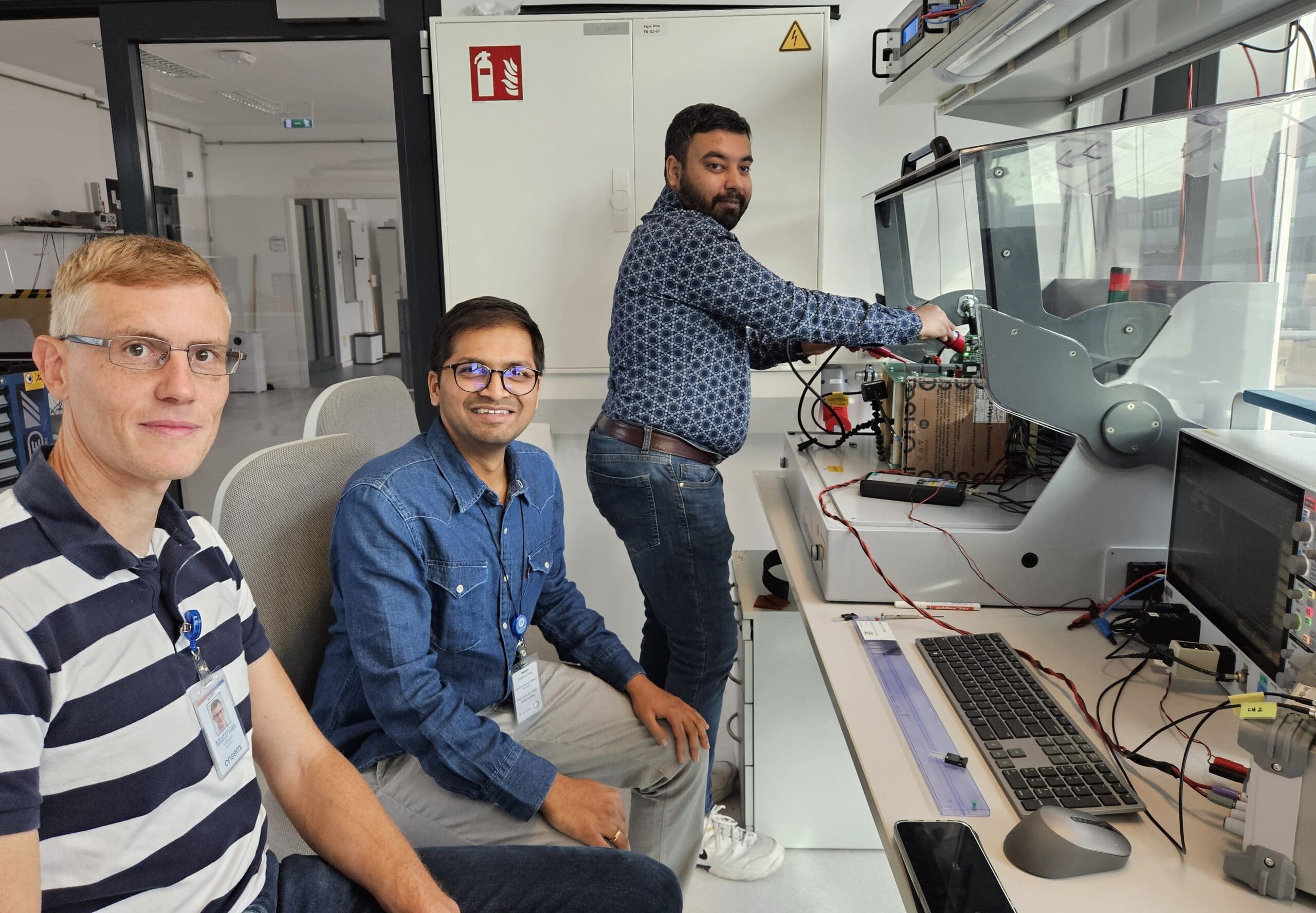 Matthias Ulmann Field Applications Manager with colleagues Sushrut and Syed in the high voltage lab at the double-pulse test setup for SiC MOSFETs