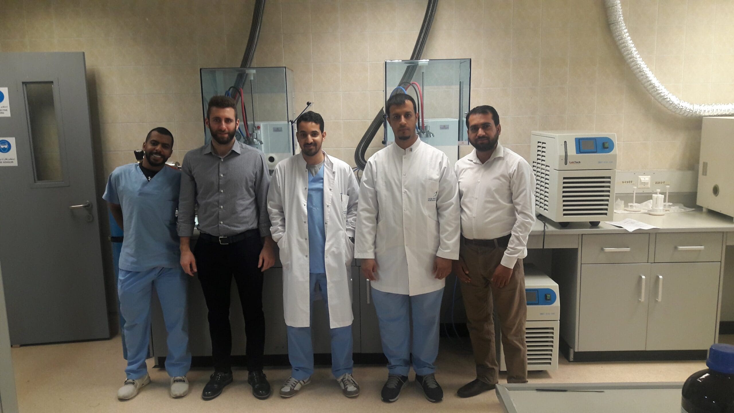 SYED INAYAT ALI SHAH with colleagues in lab with instrumentation and calibration equipment